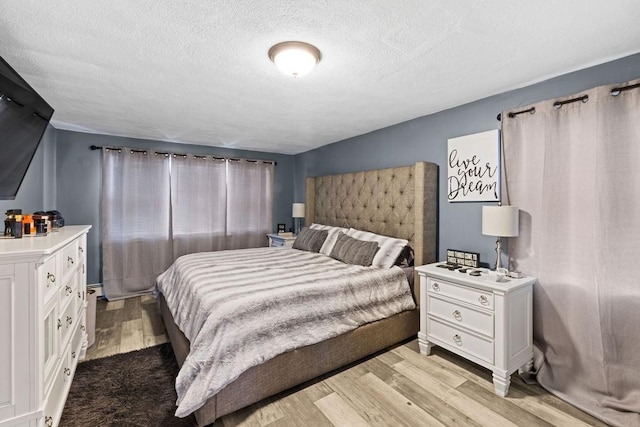 bedroom with a textured ceiling and light wood-type flooring