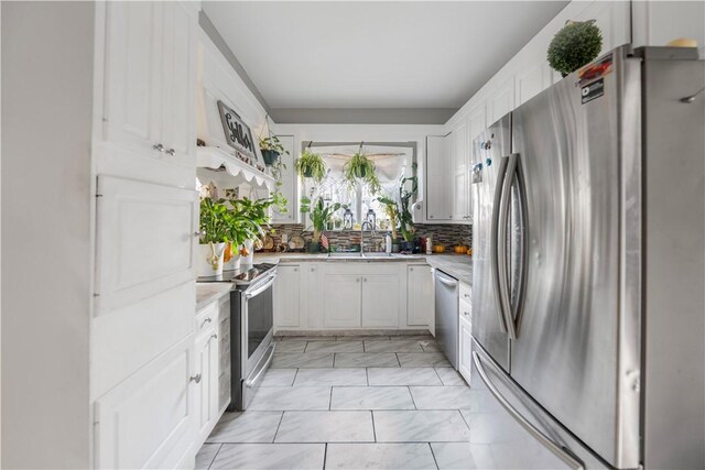 kitchen featuring decorative backsplash, white cabinets, appliances with stainless steel finishes, and sink