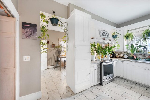 kitchen with decorative backsplash, stainless steel electric stove, and white cabinetry