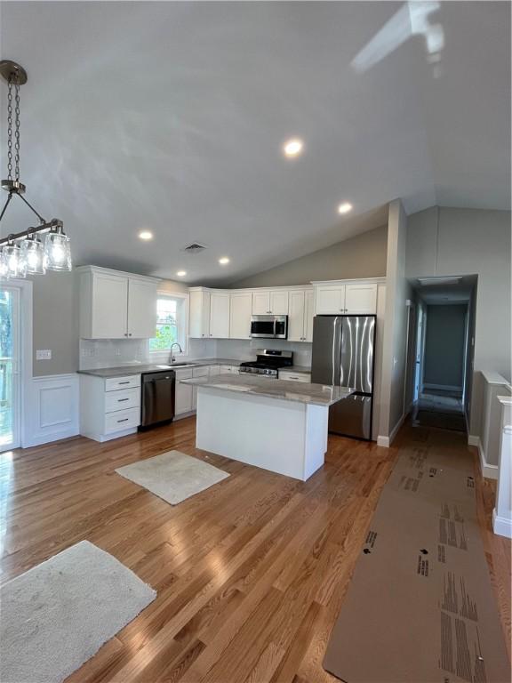 kitchen featuring appliances with stainless steel finishes, a center island, pendant lighting, white cabinets, and sink