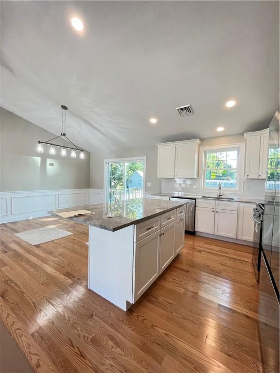 kitchen featuring sink, white cabinetry, a center island, and dark stone counters