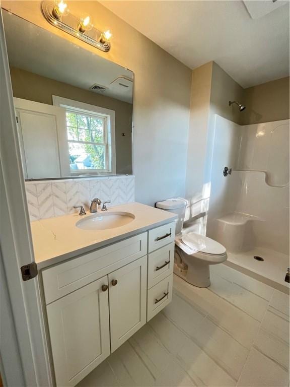 bathroom featuring toilet, vanity, walk in shower, and tasteful backsplash