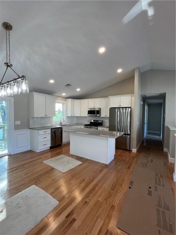 kitchen with appliances with stainless steel finishes, a center island, decorative light fixtures, white cabinetry, and decorative backsplash