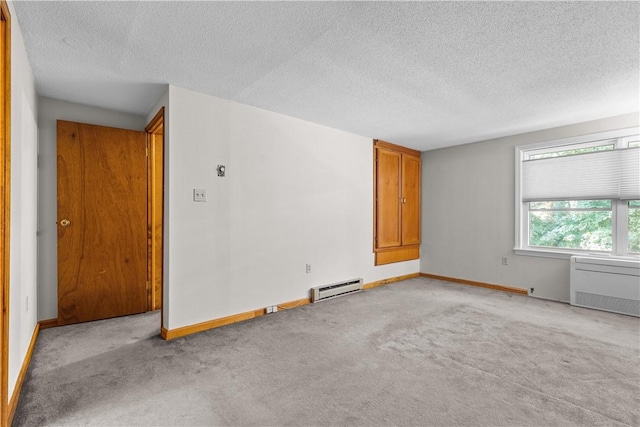 empty room featuring light colored carpet, a textured ceiling, a baseboard heating unit, and radiator heating unit