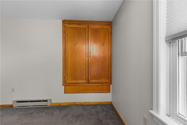 empty room featuring carpet floors, a baseboard radiator, and a healthy amount of sunlight