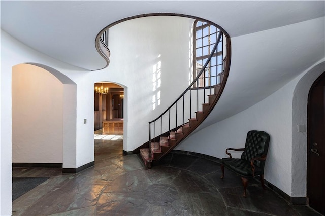 stairway featuring a notable chandelier