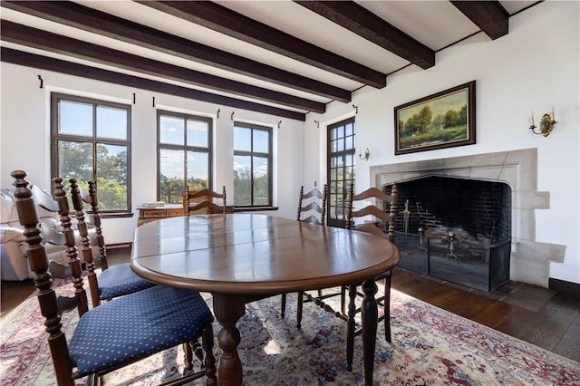 dining room featuring beam ceiling, a high end fireplace, dark hardwood / wood-style floors, and a healthy amount of sunlight