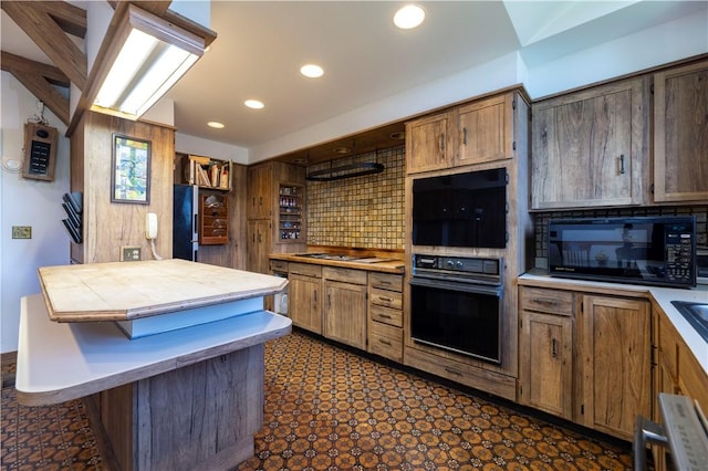 kitchen featuring a kitchen bar, a center island, decorative backsplash, and black appliances