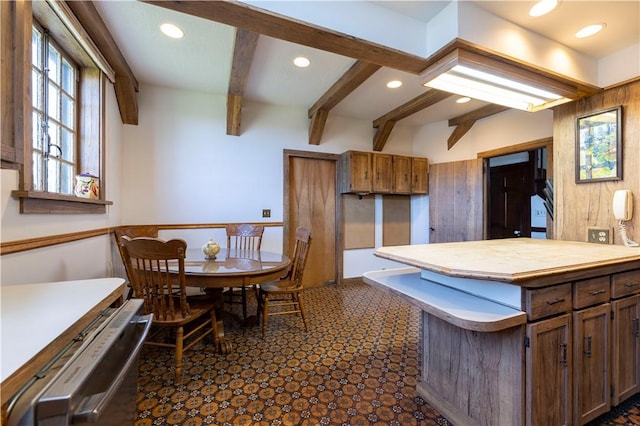 kitchen with a kitchen island, beam ceiling, and wood walls