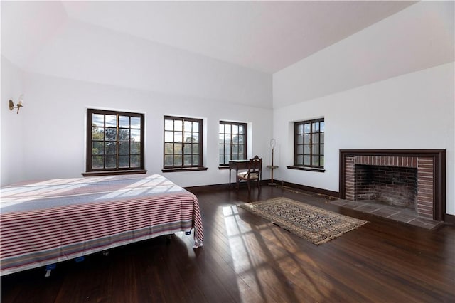 bedroom featuring a raised ceiling, a brick fireplace, and dark hardwood / wood-style floors