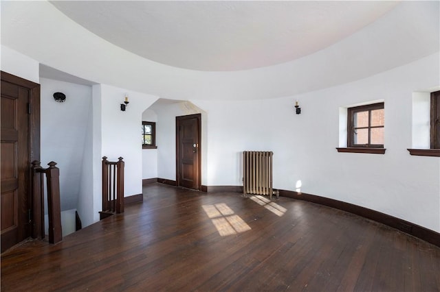 unfurnished room with radiator and dark wood-type flooring