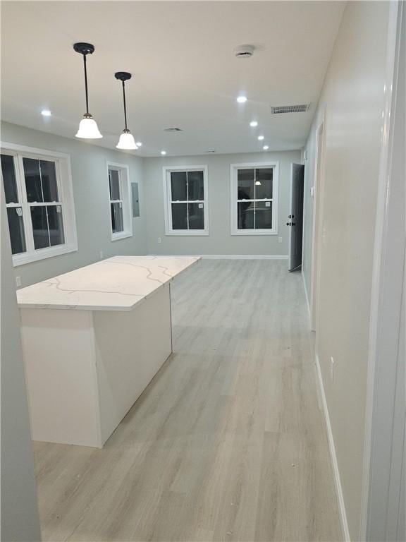 kitchen featuring light stone counters, light hardwood / wood-style floors, and pendant lighting