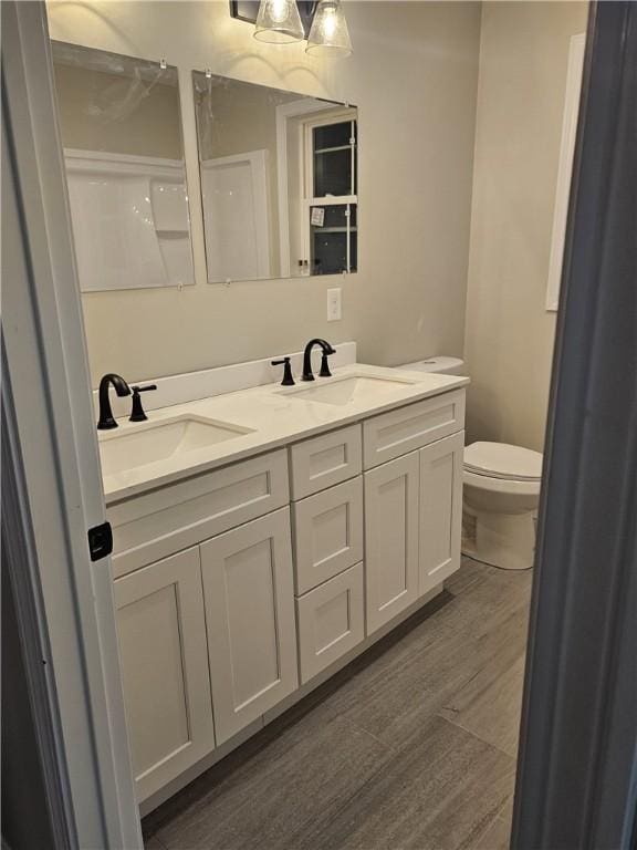 bathroom with toilet, hardwood / wood-style flooring, and vanity