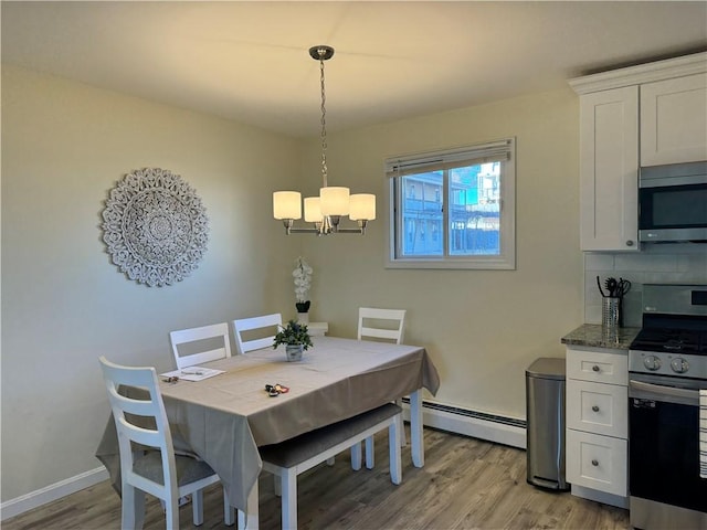 dining space with light wood-type flooring, a chandelier, and a baseboard radiator