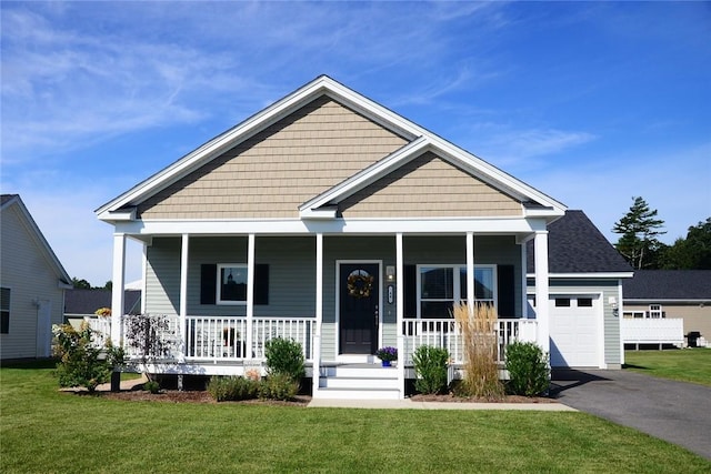 view of front of property featuring covered porch, a front yard, and a garage