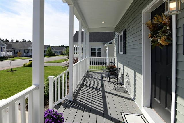 wooden terrace featuring a yard and covered porch