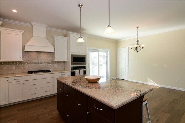 kitchen with premium range hood, stainless steel appliances, dark hardwood / wood-style floors, hanging light fixtures, and white cabinets