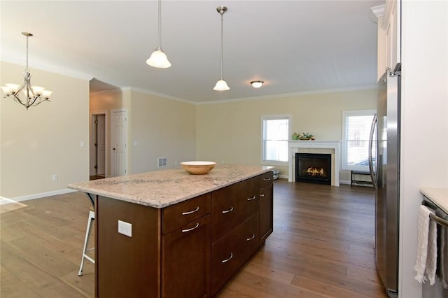 kitchen featuring a center island, stainless steel appliances, ornamental molding, hardwood / wood-style flooring, and a breakfast bar