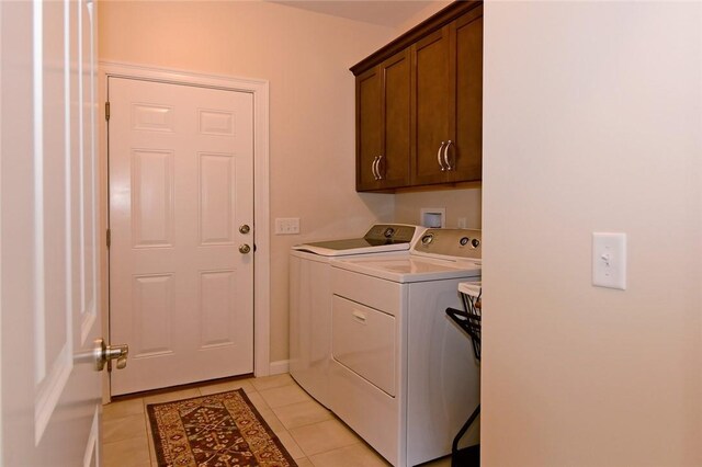 laundry area with cabinets, separate washer and dryer, and light tile patterned floors