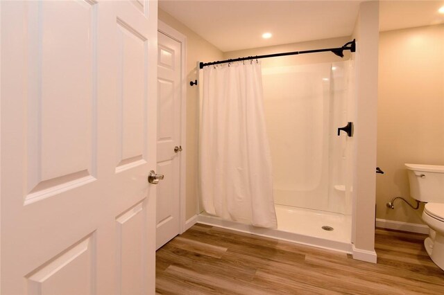 bathroom featuring toilet, hardwood / wood-style flooring, and walk in shower