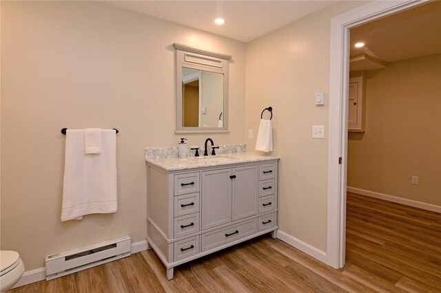 bathroom featuring a baseboard heating unit, toilet, hardwood / wood-style flooring, and vanity