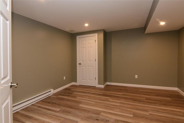 basement featuring wood-type flooring and a baseboard radiator