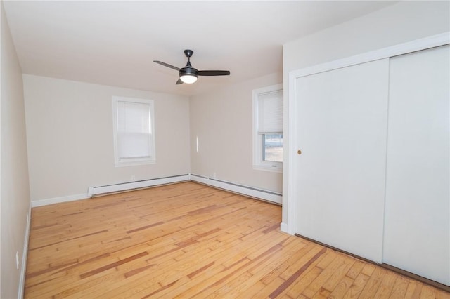 unfurnished bedroom featuring ceiling fan, a closet, a baseboard radiator, and light hardwood / wood-style floors