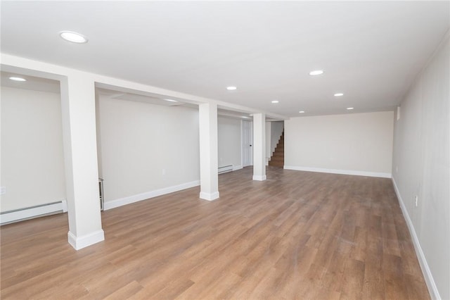 basement with light hardwood / wood-style flooring and a baseboard radiator