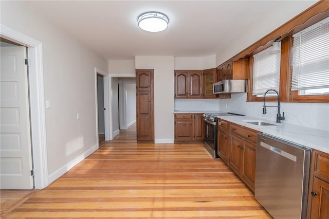 kitchen featuring decorative backsplash, sink, appliances with stainless steel finishes, and light hardwood / wood-style flooring