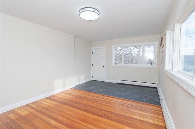 spare room with a baseboard heating unit and wood-type flooring