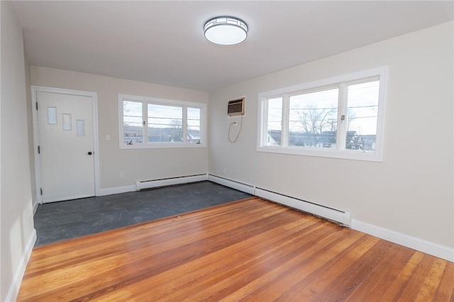 unfurnished room featuring hardwood / wood-style flooring, a baseboard radiator, and a wall mounted air conditioner