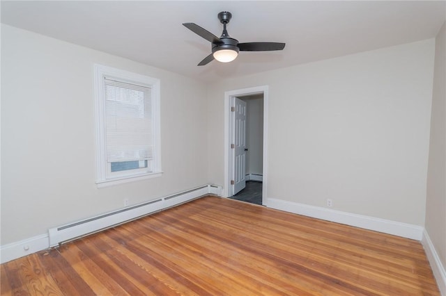 empty room featuring baseboard heating, a wealth of natural light, hardwood / wood-style floors, and ceiling fan