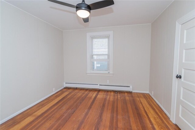 spare room with ceiling fan, baseboard heating, and dark hardwood / wood-style flooring