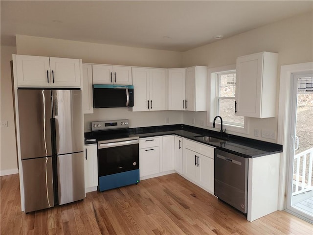 kitchen featuring appliances with stainless steel finishes, light hardwood / wood-style flooring, white cabinetry, and sink