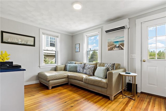 living room featuring a wall mounted air conditioner, light hardwood / wood-style flooring, and ornamental molding