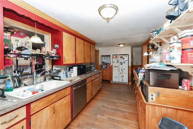 kitchen with hanging light fixtures, appliances with stainless steel finishes, sink, and light hardwood / wood-style flooring