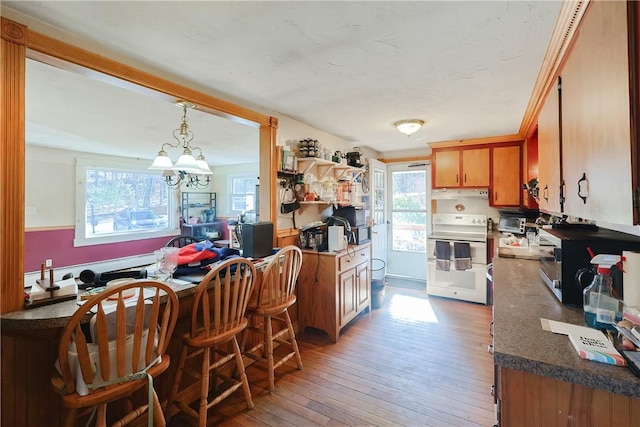 kitchen with a chandelier, range, light hardwood / wood-style floors, and decorative light fixtures