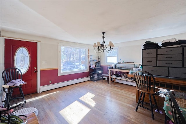 dining area featuring baseboard heating, an inviting chandelier, and hardwood / wood-style floors