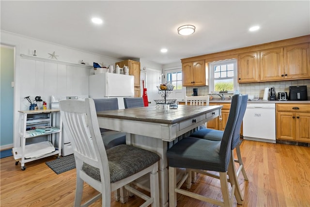 kitchen with white appliances, light hardwood / wood-style flooring, and tasteful backsplash