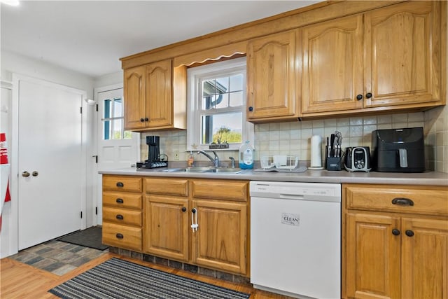 kitchen with sink, white dishwasher, and decorative backsplash