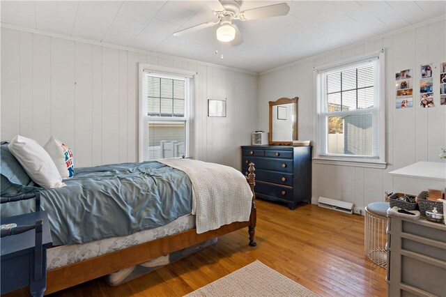 bedroom featuring a baseboard heating unit, ceiling fan, crown molding, and hardwood / wood-style floors