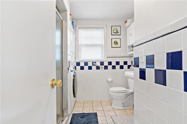 bathroom with toilet, tile patterned flooring, tile walls, and walk in shower