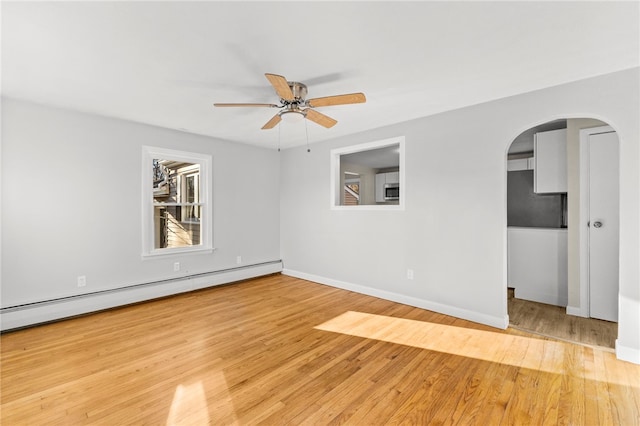 spare room with ceiling fan, a baseboard heating unit, and light hardwood / wood-style flooring