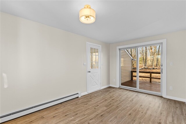 spare room with baseboard heating and light hardwood / wood-style flooring