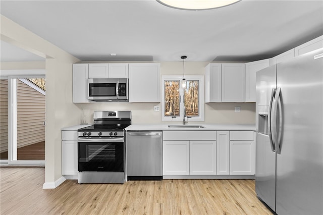 kitchen with light hardwood / wood-style floors, stainless steel appliances, decorative light fixtures, white cabinets, and sink