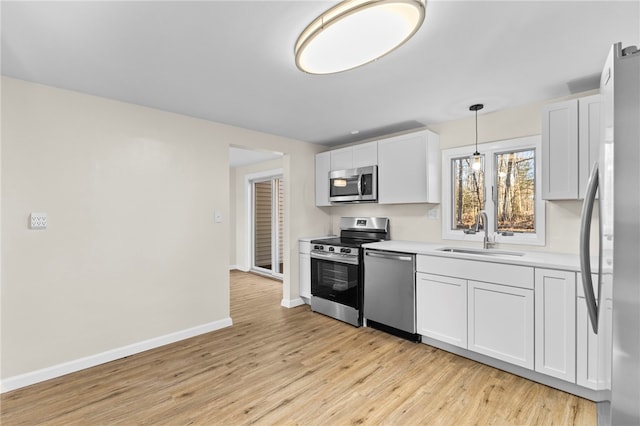 kitchen with decorative light fixtures, sink, white cabinetry, and appliances with stainless steel finishes