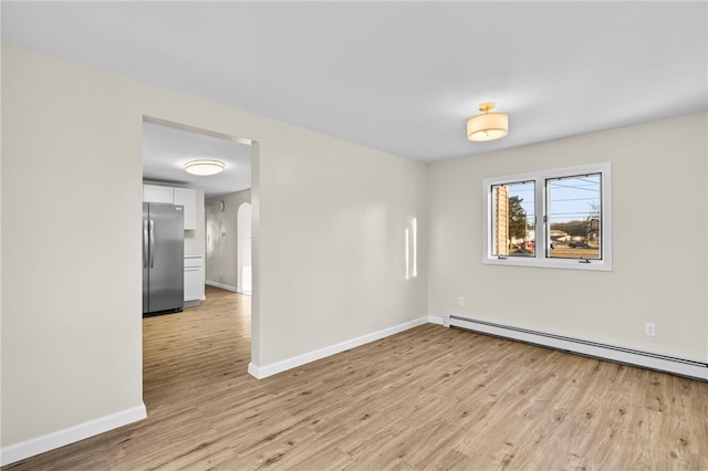 spare room with light wood-type flooring and a baseboard radiator