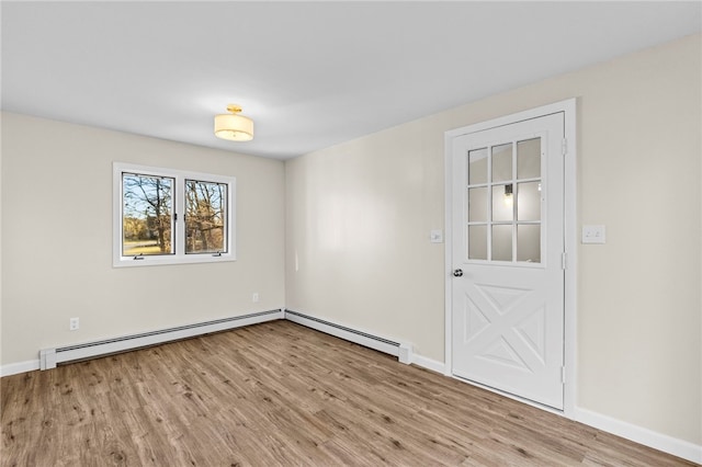 empty room featuring light wood-type flooring and a baseboard heating unit