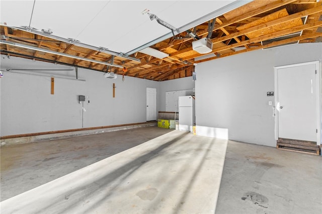 garage featuring white fridge and a garage door opener