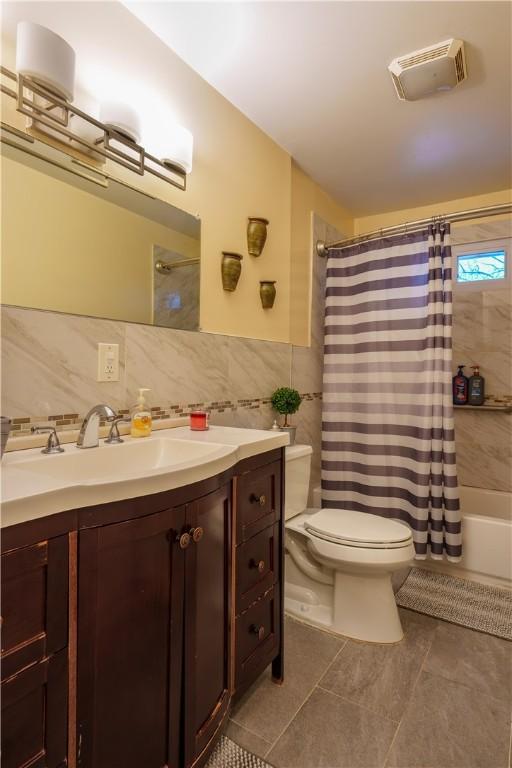 full bathroom with toilet, shower / tub combo, tile patterned floors, tile walls, and vanity